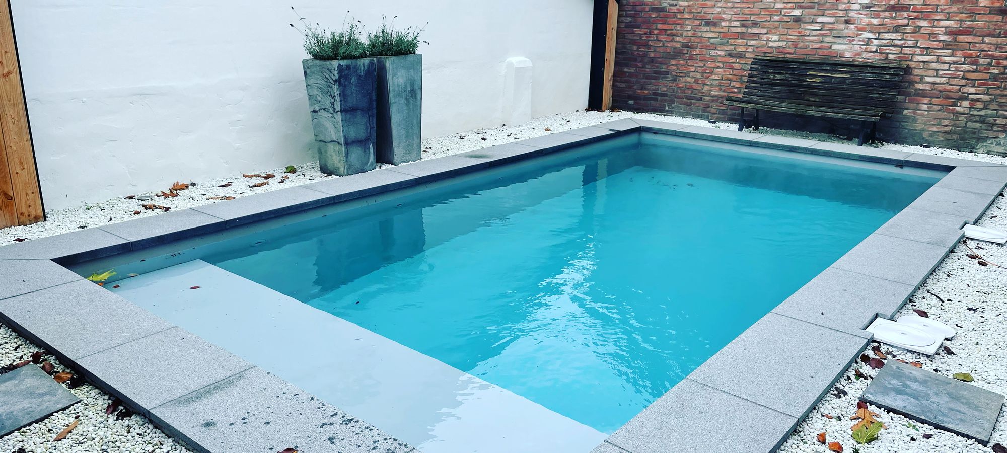 Compact zwembad in een besloten binnentuin met natuurstenen randen