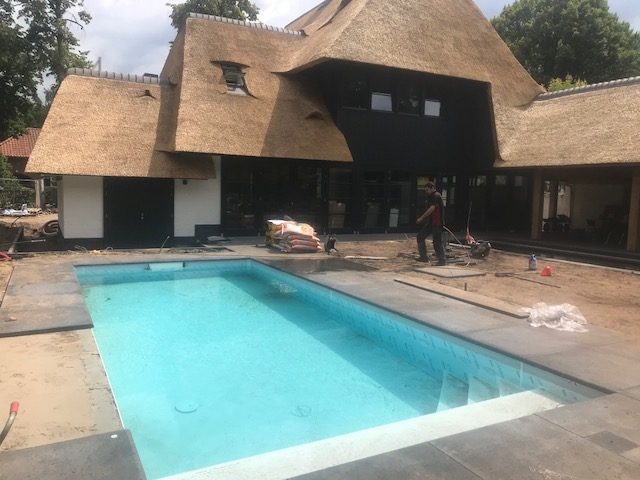 Zwembad met brede zittrap bij een rietgedekte villa in Vught, vlak voor oplevering